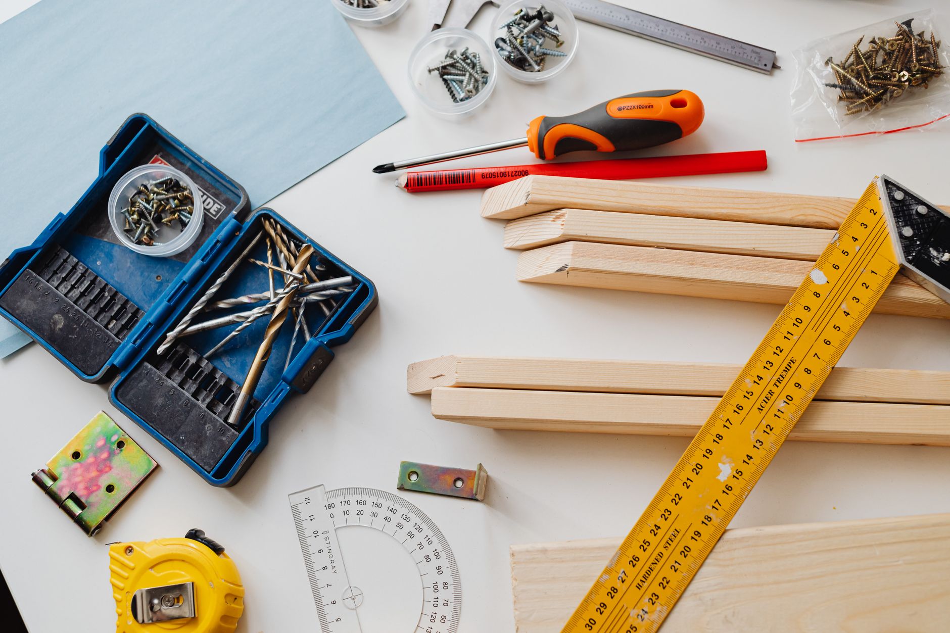 A top view of various woodworking tools and materials on a white table. — Avoid property loss through awareness of adverse po