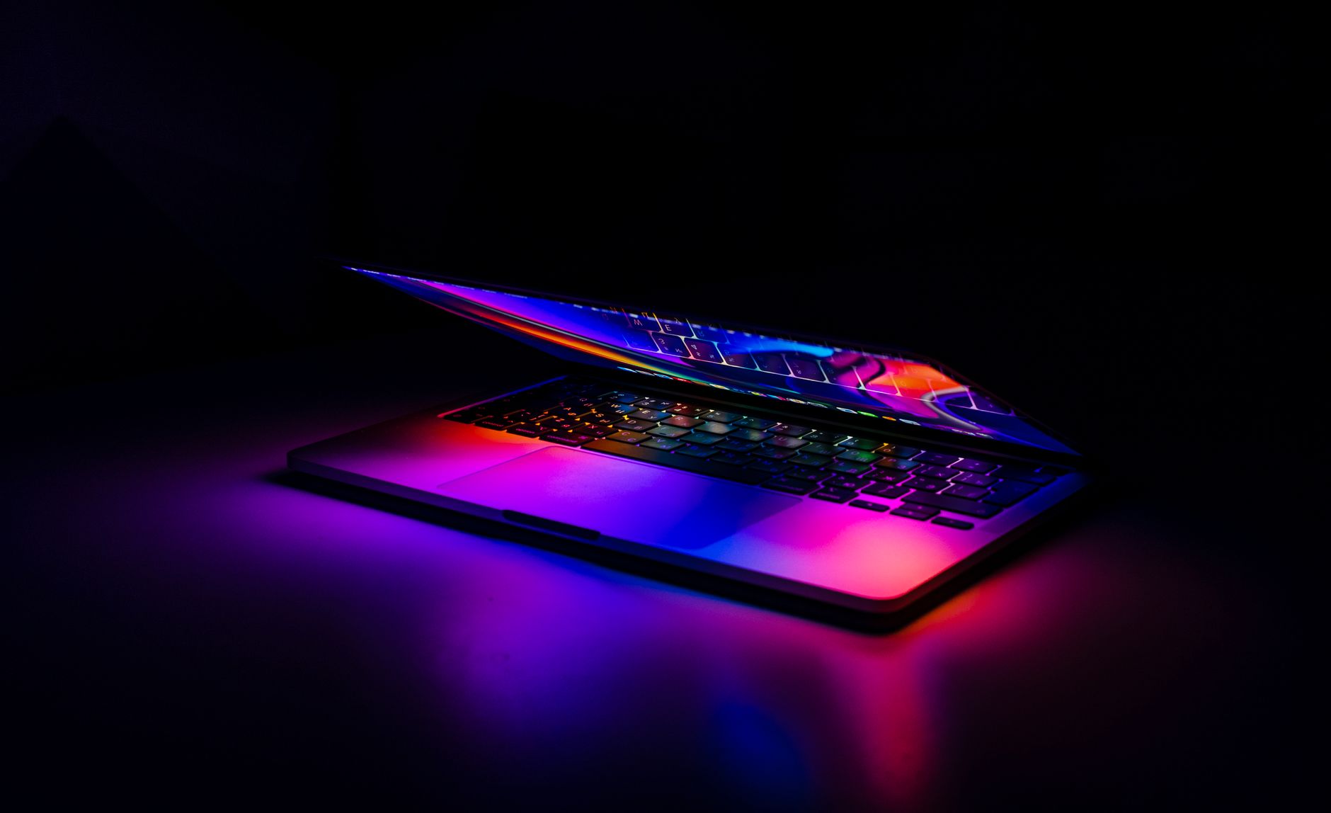 A partially closed MacBook with vibrant, colorful light reflections on a dark background. — Precision Optimization Strategies
